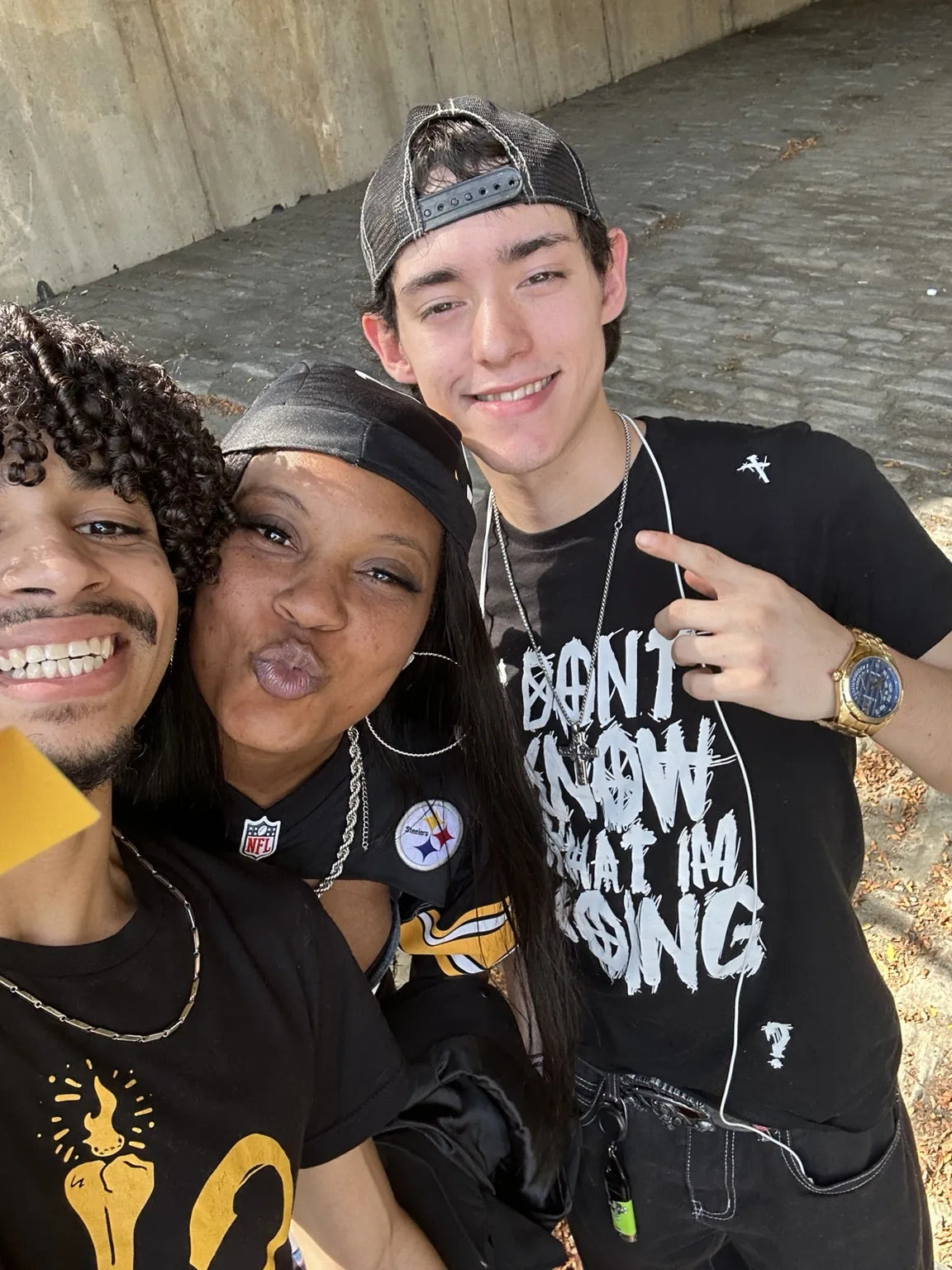 Three people taking a selfie while one wears a black and yellow Rizo 412 shirt