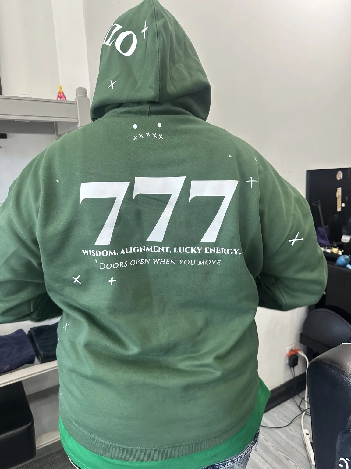 A person wearing a green Rizo 777 hoodie shown from the back