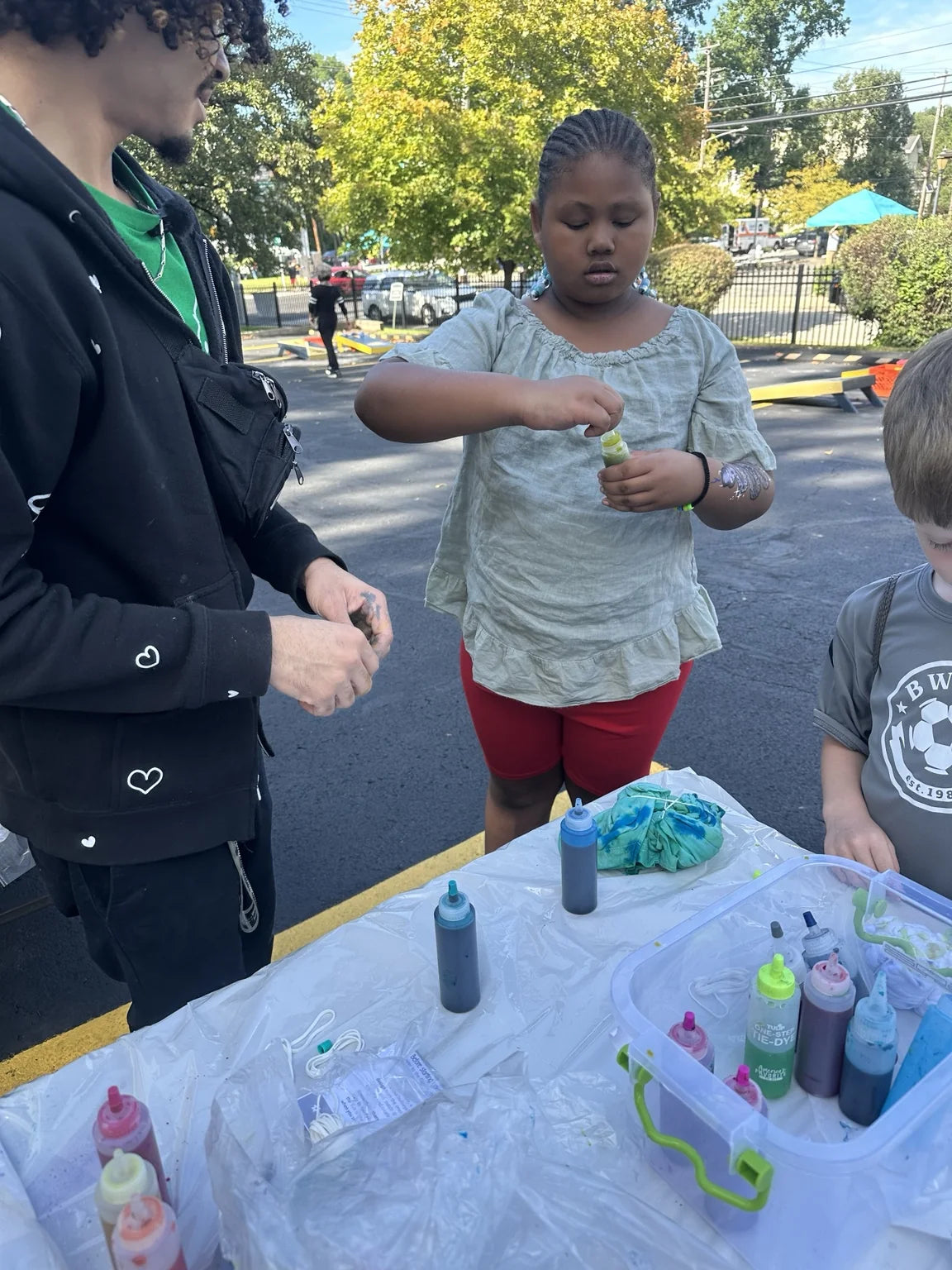 A child working on a shirt with dye bottles on the table