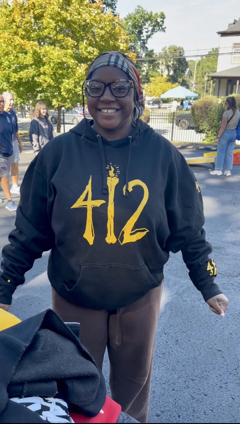 A person smiling in a black Rizo 412 hoodie at the block party