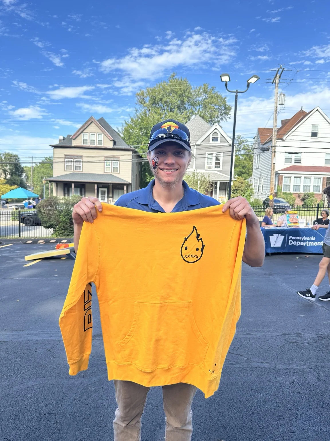 A person holding up a yellow Rizo shirt at the block party