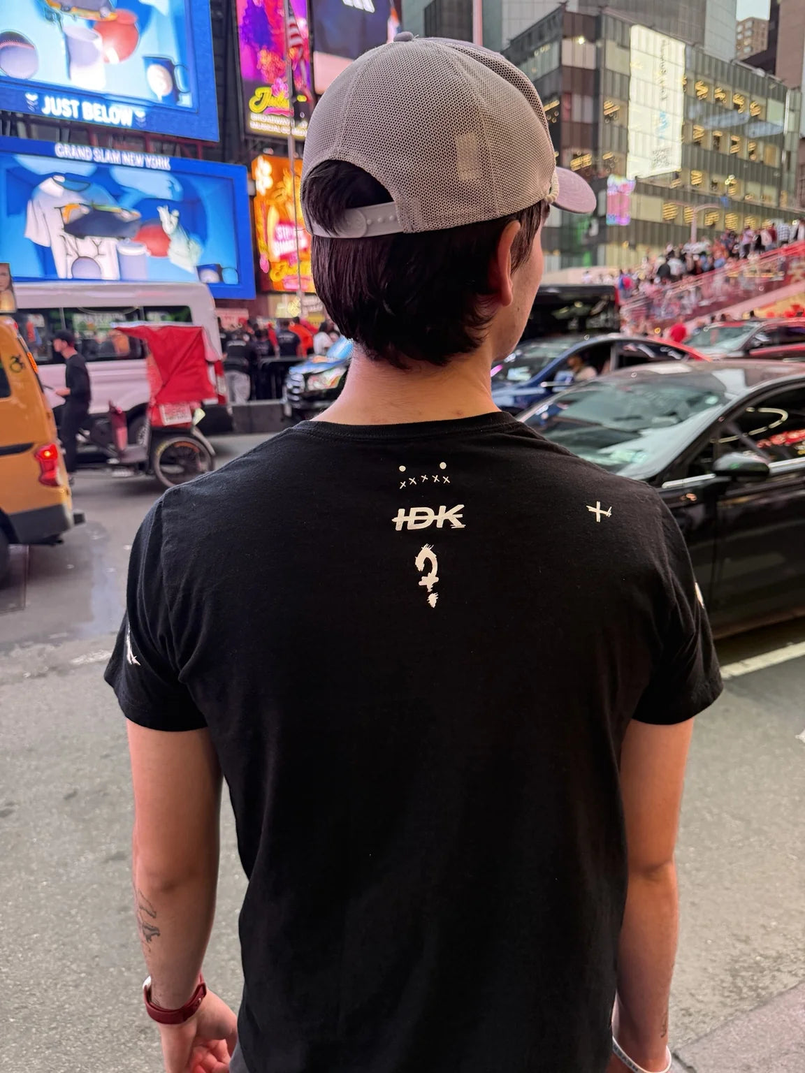 The back of a black Rizo T-shirt with small white graphics in Times Square