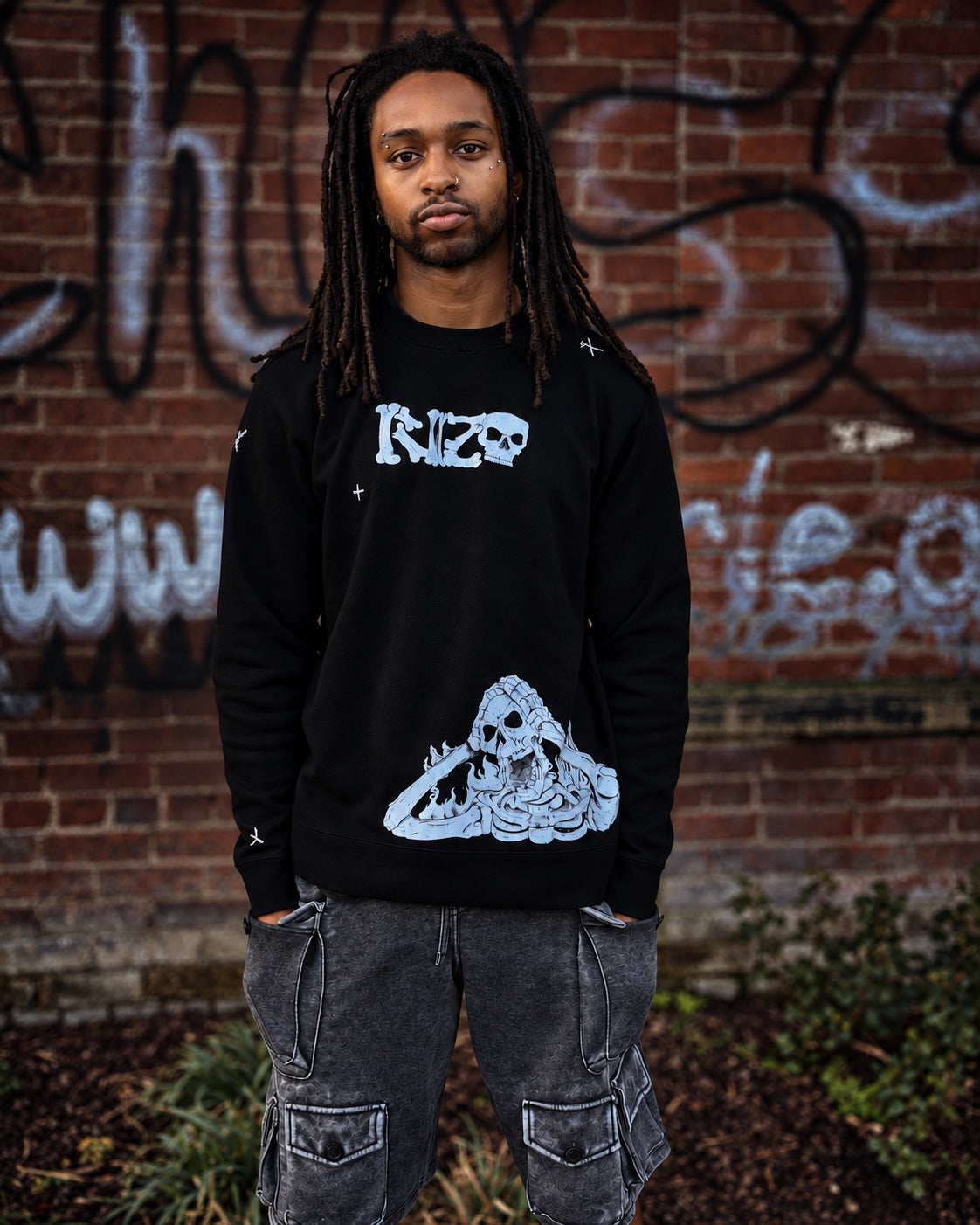 Model wearing the black RIZO Skeleton Crewneck against a graffiti-covered brick wall