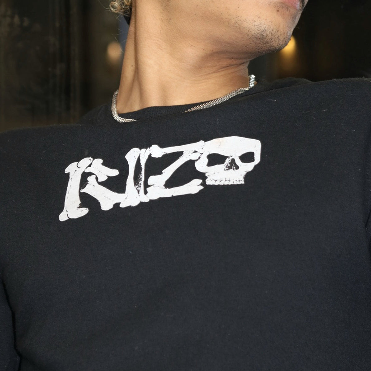 Close-up of a model wearing the real RIZO Skeleton Crewneck showing detailed bone-style RIZO lettering and skull logo