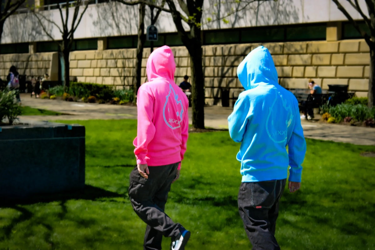 Aiden and Christian walking outdoors in pink and blue Rizo hoodies, seen from behind