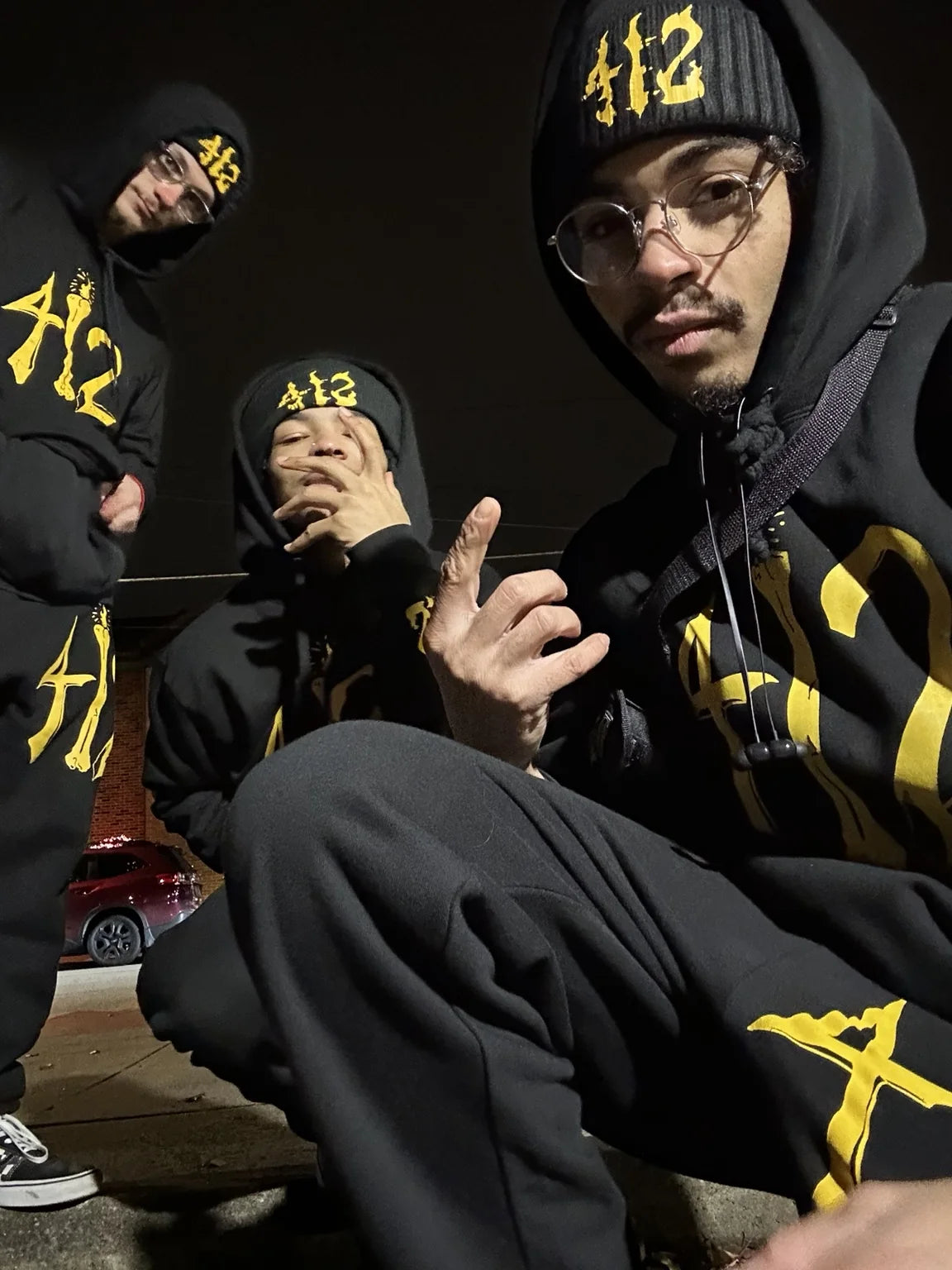 Friends wearing black and gold Rizo clothing together at night