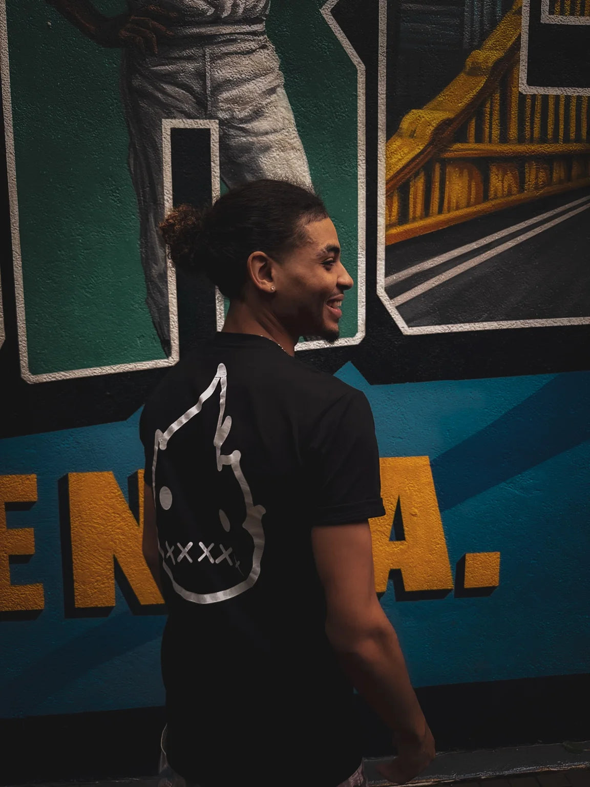 Taymar Spencer in front of a Pittsburgh mural, wearing Rizo